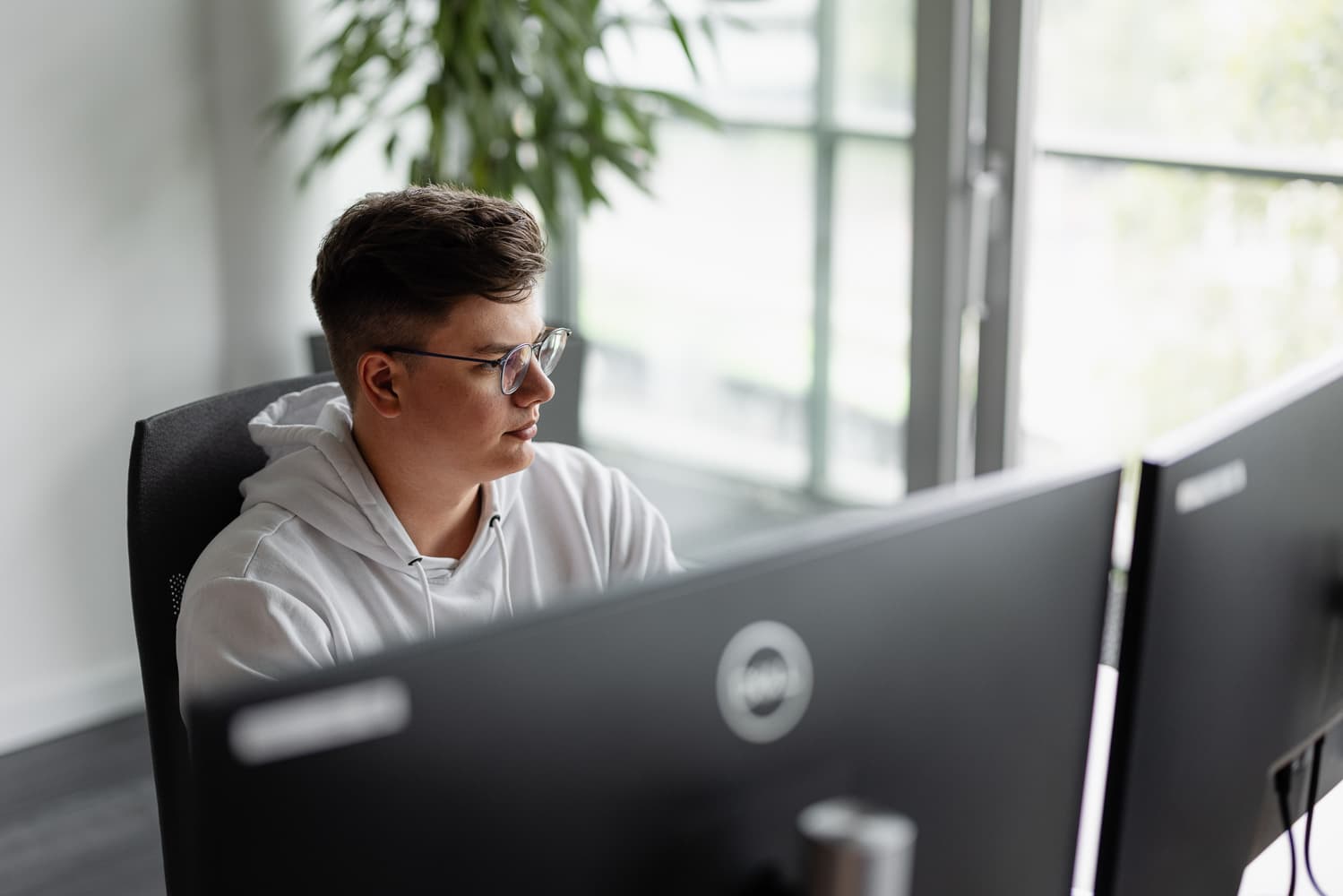 Ein Auszubildener zum Fachinformatiker Anwendungsentwicklung sitzt vor zwei Bildschirmen.