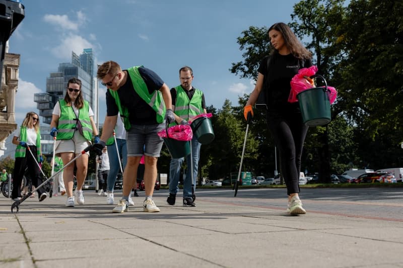 Eine Gruppe von Mitarbeitenden der WERTGARANTIE Group sammelt mit Greifzangen Müll auf.