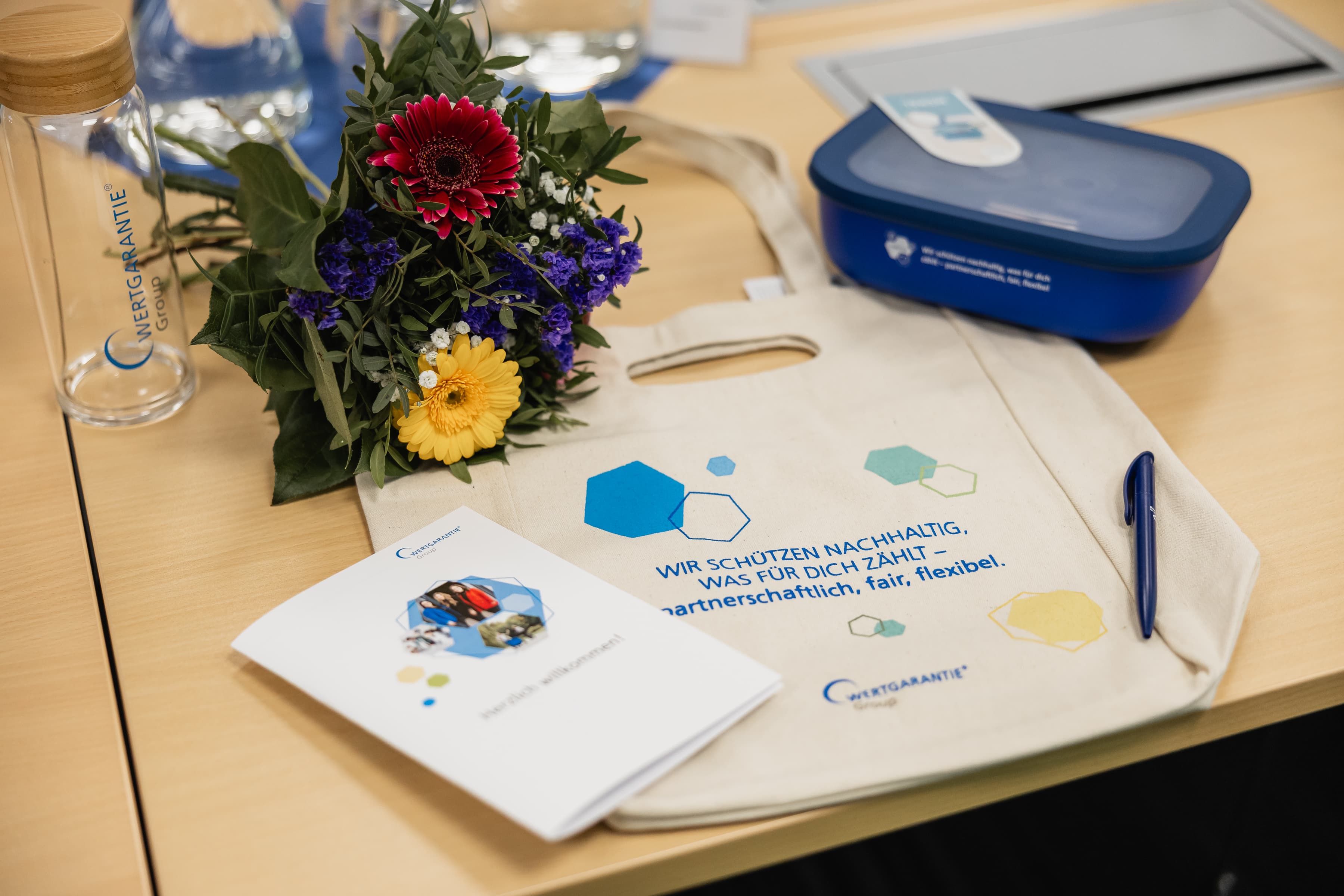 Ein geschmückter Willkommenstisch zum Onboarding für neue Mitarbeitende mit Blumenstrauß und Willkommensgeschenken.