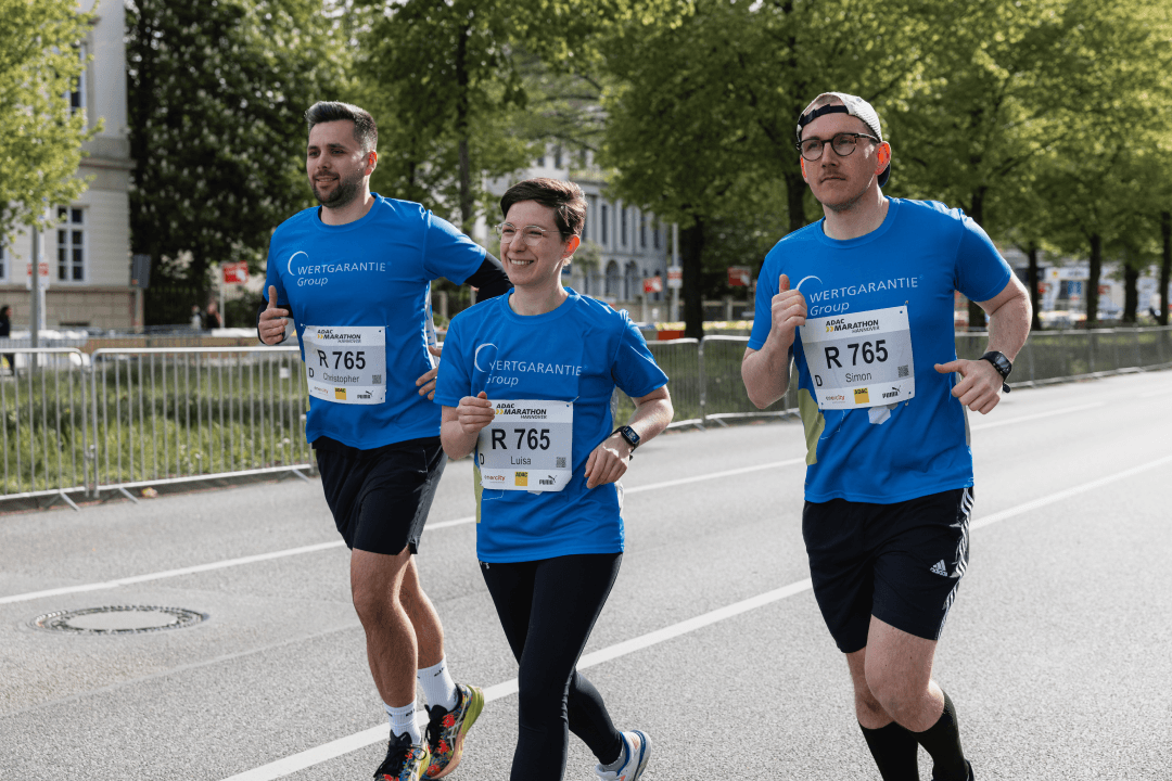 Drei Mitarbeitender der WERTGARANTIE Group laufen beim ADAC Marathon in Hannover nebeneinander her..