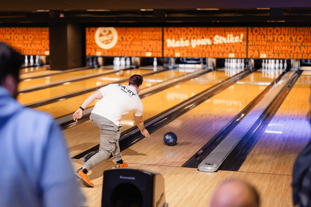 Ein Mitarbeiter wirft seine Bowlingkugel beim Firmebowling auf die Bahn.