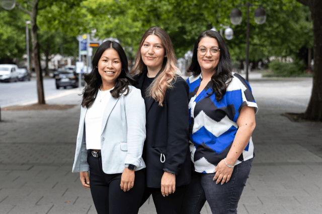 Drei Mitarbeitende aus dem Personalservice posieren nebeneinander auf dem Aegidientorplatz.
