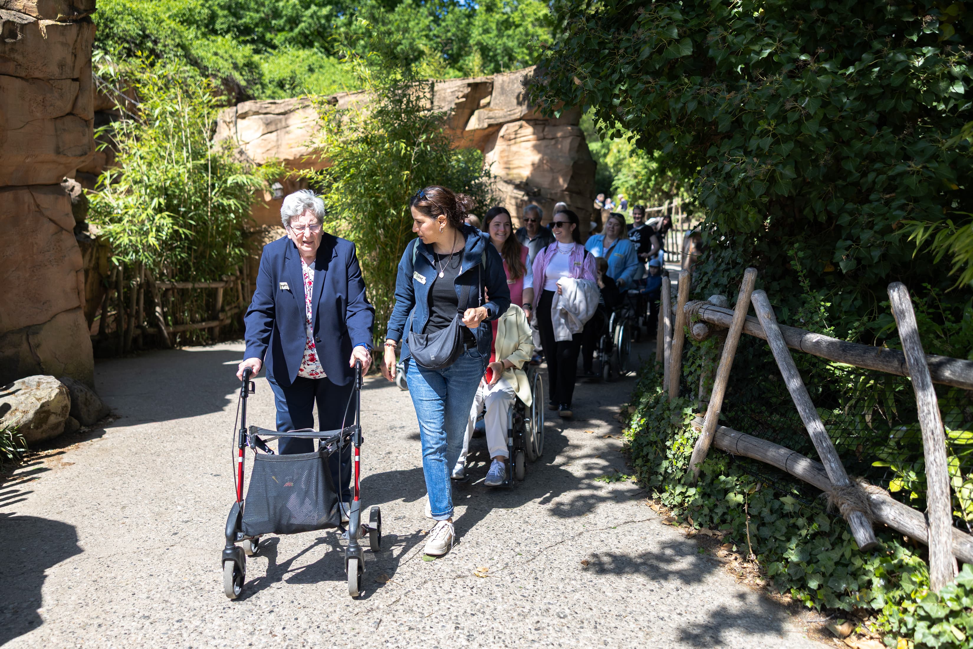Eine Mitarbeiterin läuft während eines Corporate Volunteering Einsatzes mit einer Seniorin mit Rollator durch den Zoo Hannover.