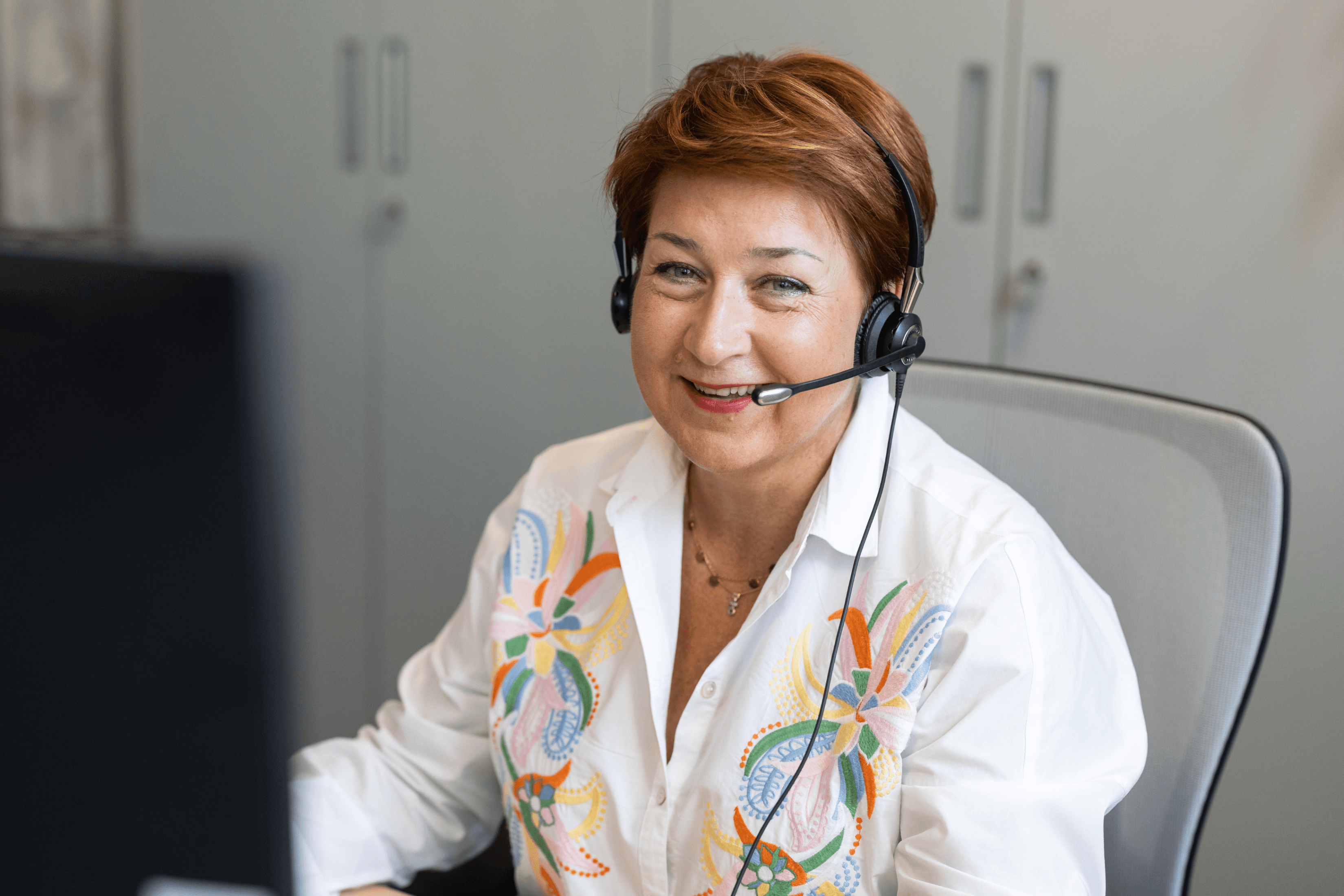 Eine Mitarbeiterin auf dem Kundenservice der WERTGARANTIE Group mit Headset.