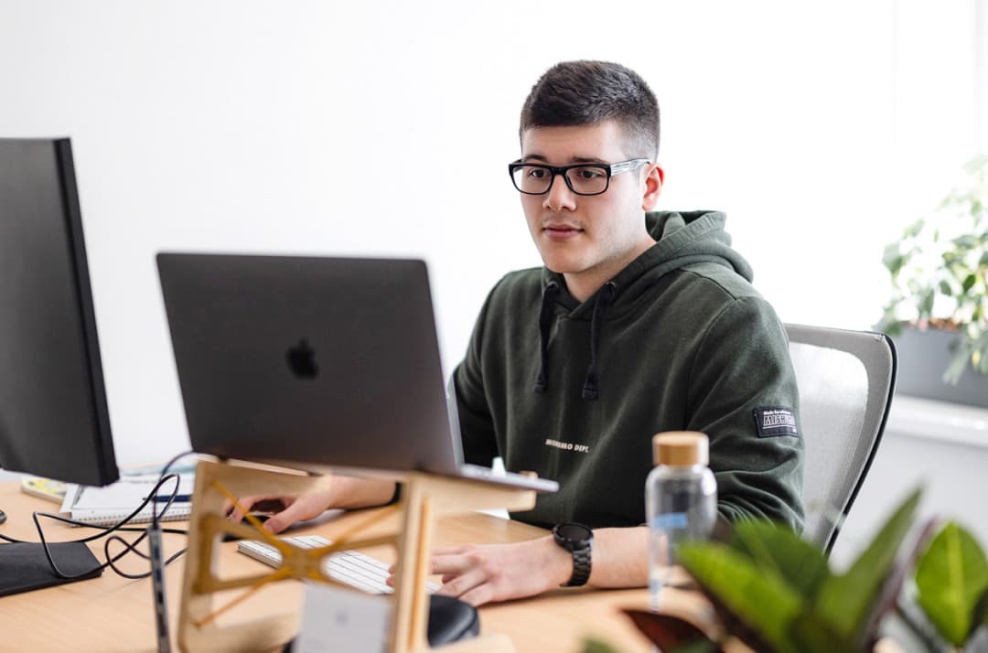 Ein Auszubildener zum Fachinformatiker Systemintegration sitzt vor zwei Bildschirmen.