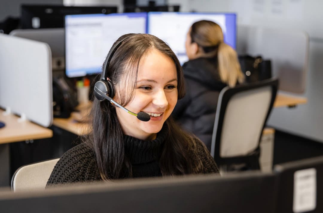 Eine Auszubildene sitzt mit einem Headset vor einem Bildschirm.