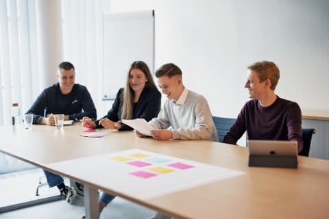 Duale Studenten und Studentinnen sitzen an einem Tisch mit Karteikarten