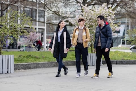 Drei Studierende der WERTGARANTIE Group gehen draußen nebeneinander her.