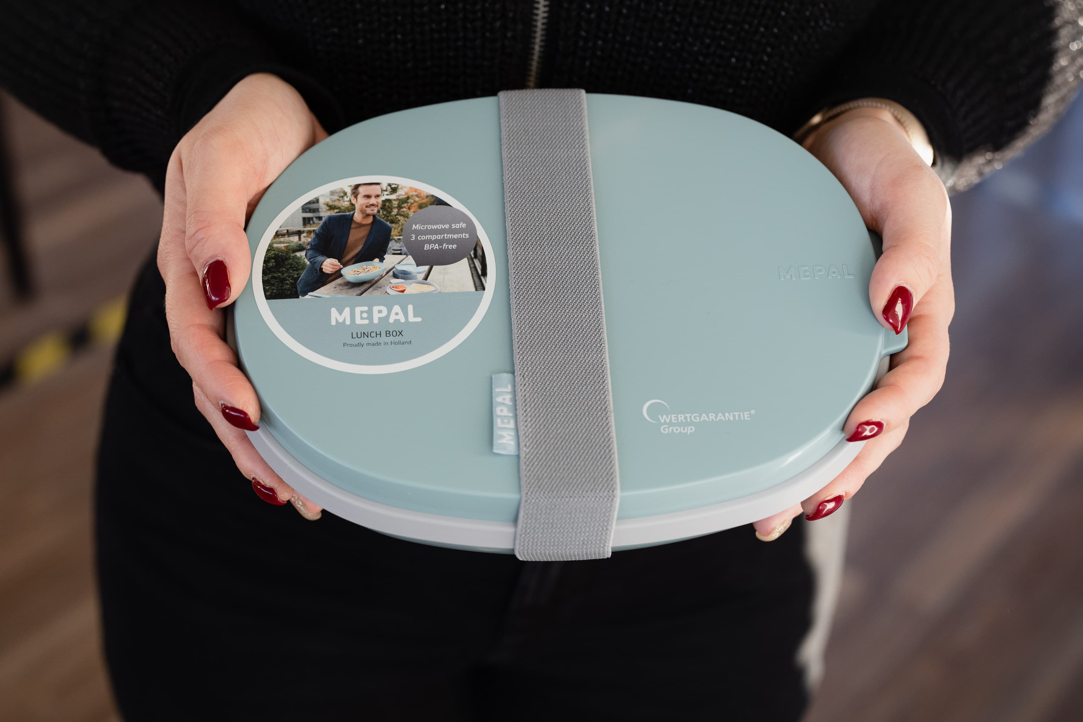Eine Person hält eine mintfarbene, ovale Mepal Lunchbox in den Händen.