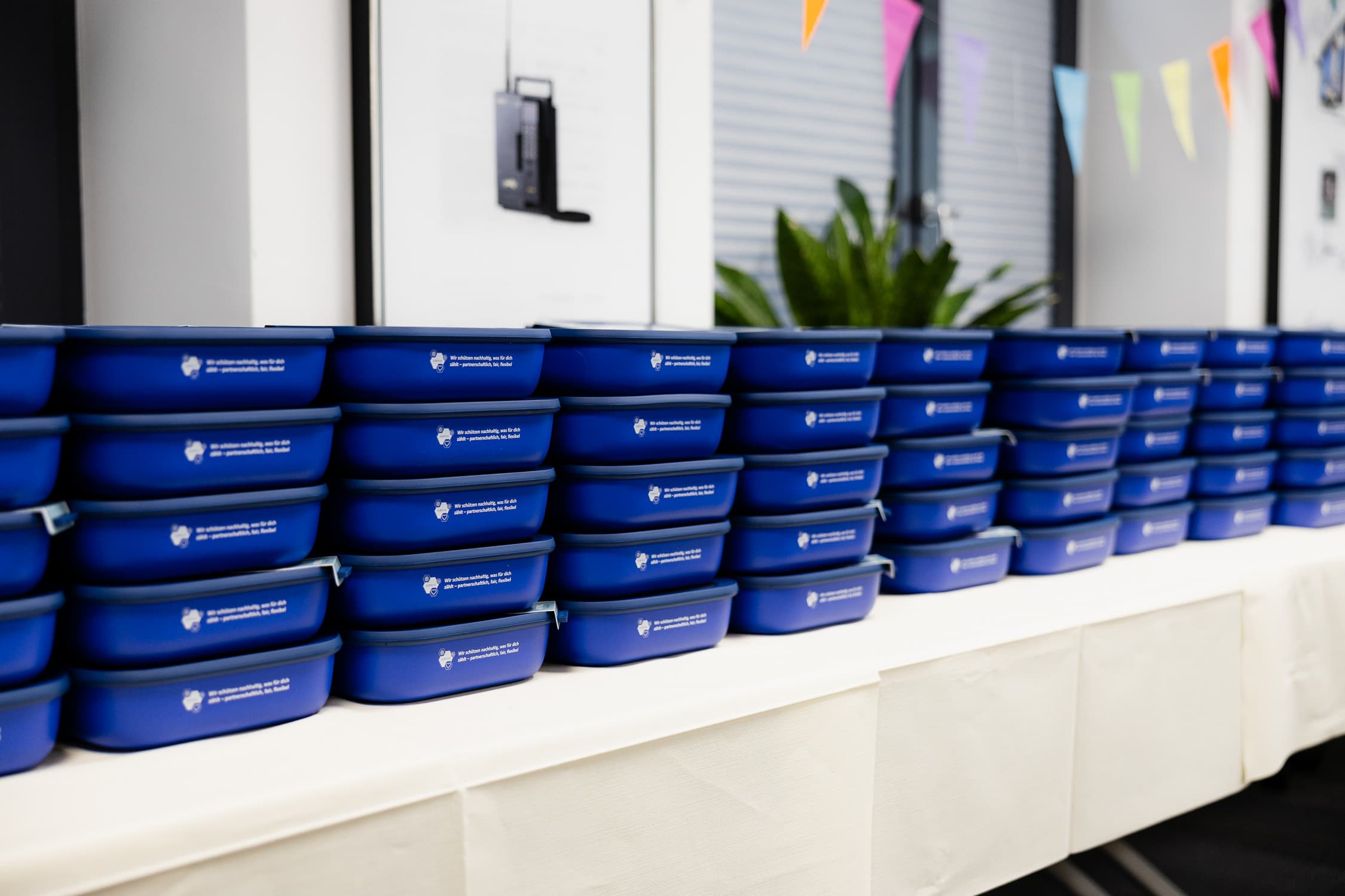 Viele blaue Mepal Vorratsdosen sind als Mitarbeitergeschenke nebeneinander aufgestapelt.