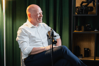 Außendienstleiter Maurice Jöhler sitzt in einem Podcaststudio. Vor ihm ist ein Mikrofon aufgebaut.