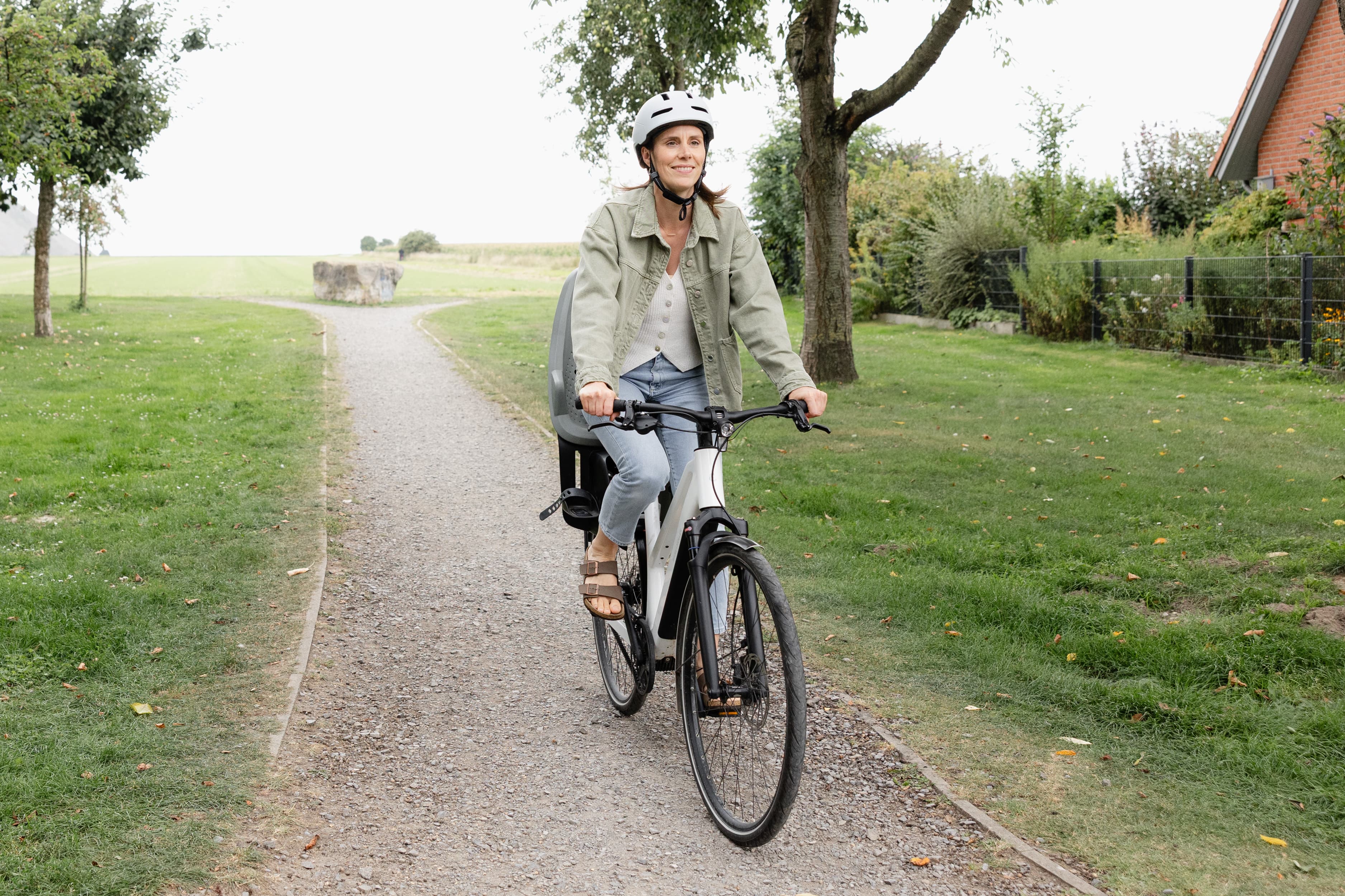 Eine Mitarbeiterin fährt auf dem Fahrrad im Grünen.