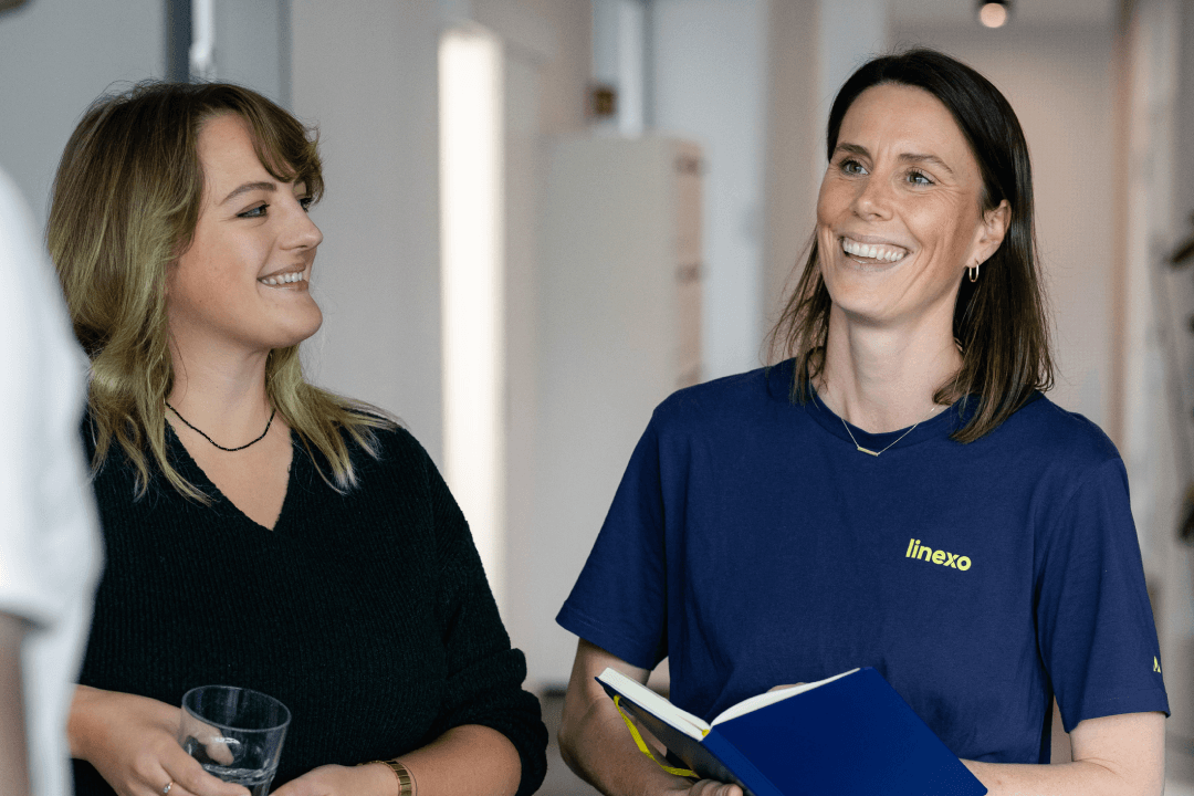 Zwei Mitarbeiterinnen der WERTGARANTIE Group stehen nebeneinander und tauschen sich aus.