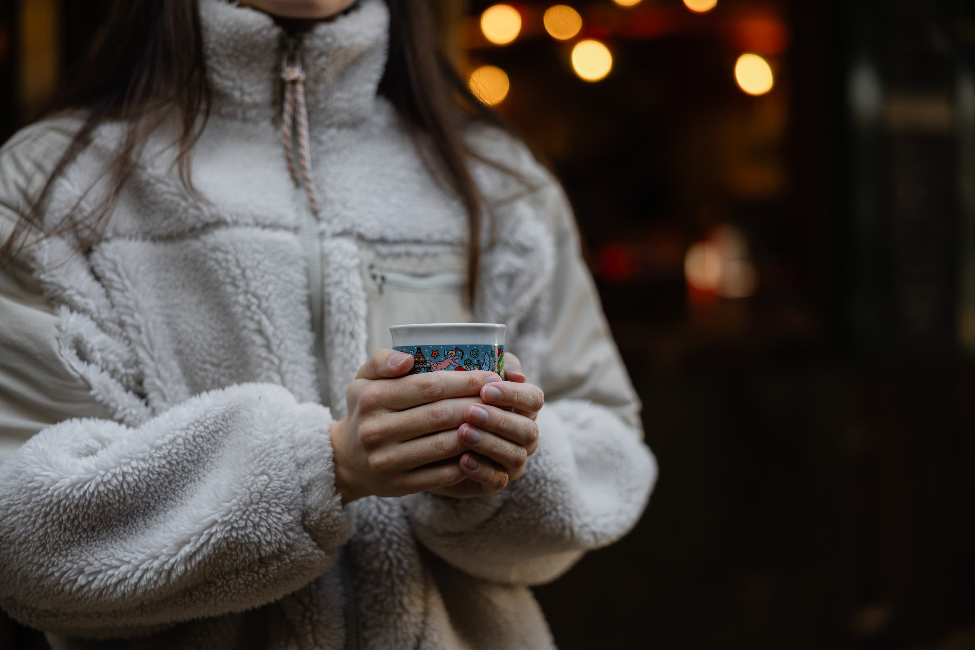 Eine Mitarbeiterin der WERTGARANTIE Group hält eine Tasse mit Glühwein in beiden Händen und wärmt sich.