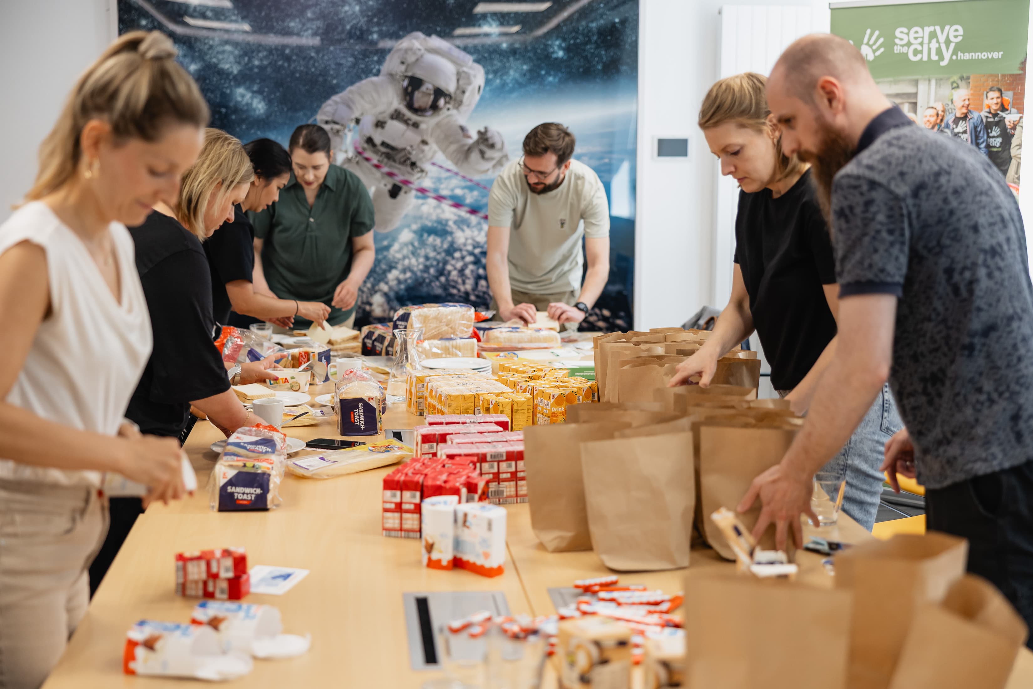 Mitarbeitende der WERTGARANTIE Group packen Lebensmittel um wohnungslose Menschen in Hannover zu versorgen.